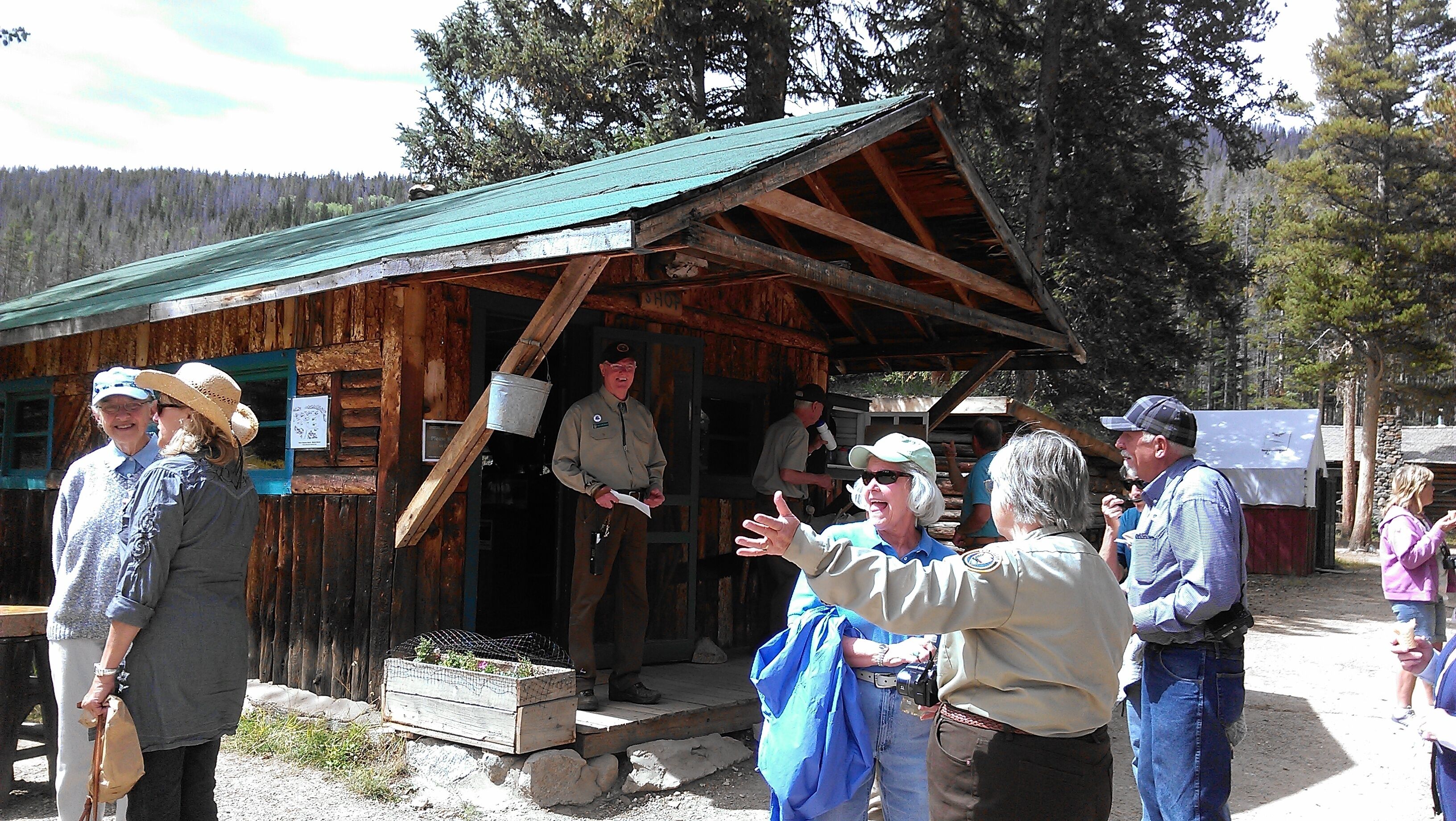 A rustic wooden cabin with a green roof, a wooden porch, and a sign that reads "Shop."