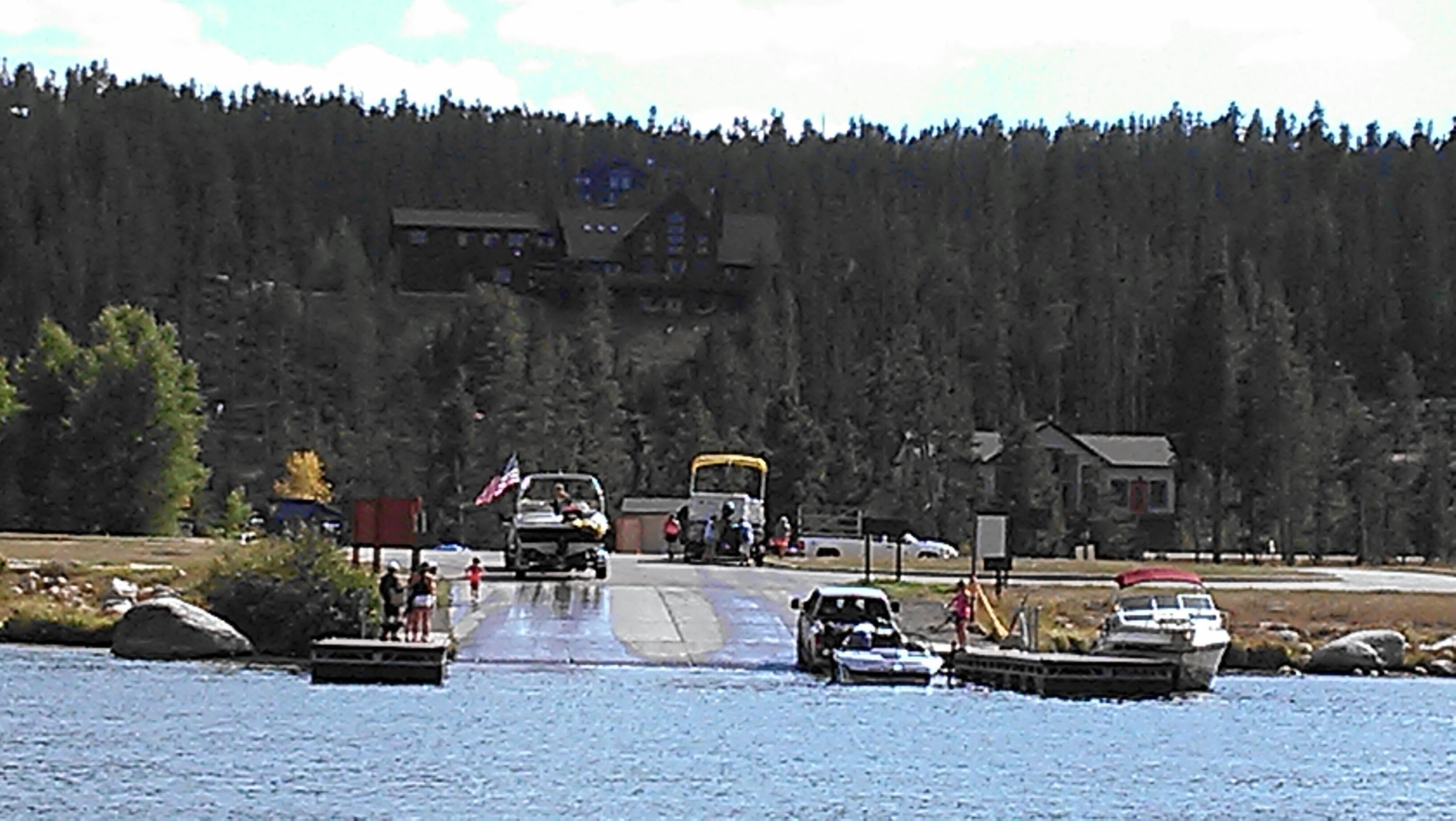 A dock with boats, a small building, and a forested hill in the background.