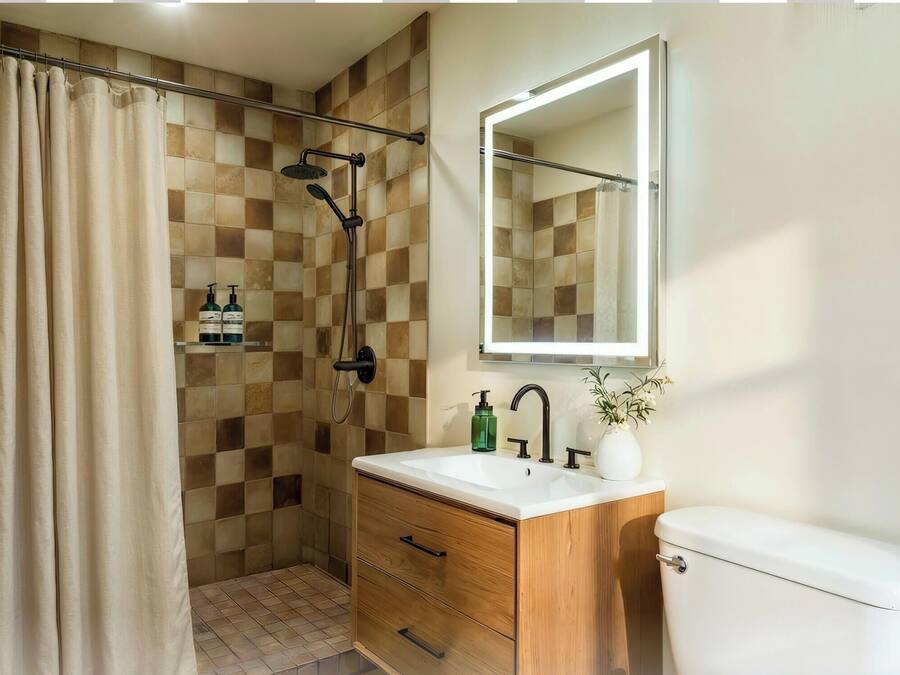 A bathroom with a shower, toilet, sink, and mirror.