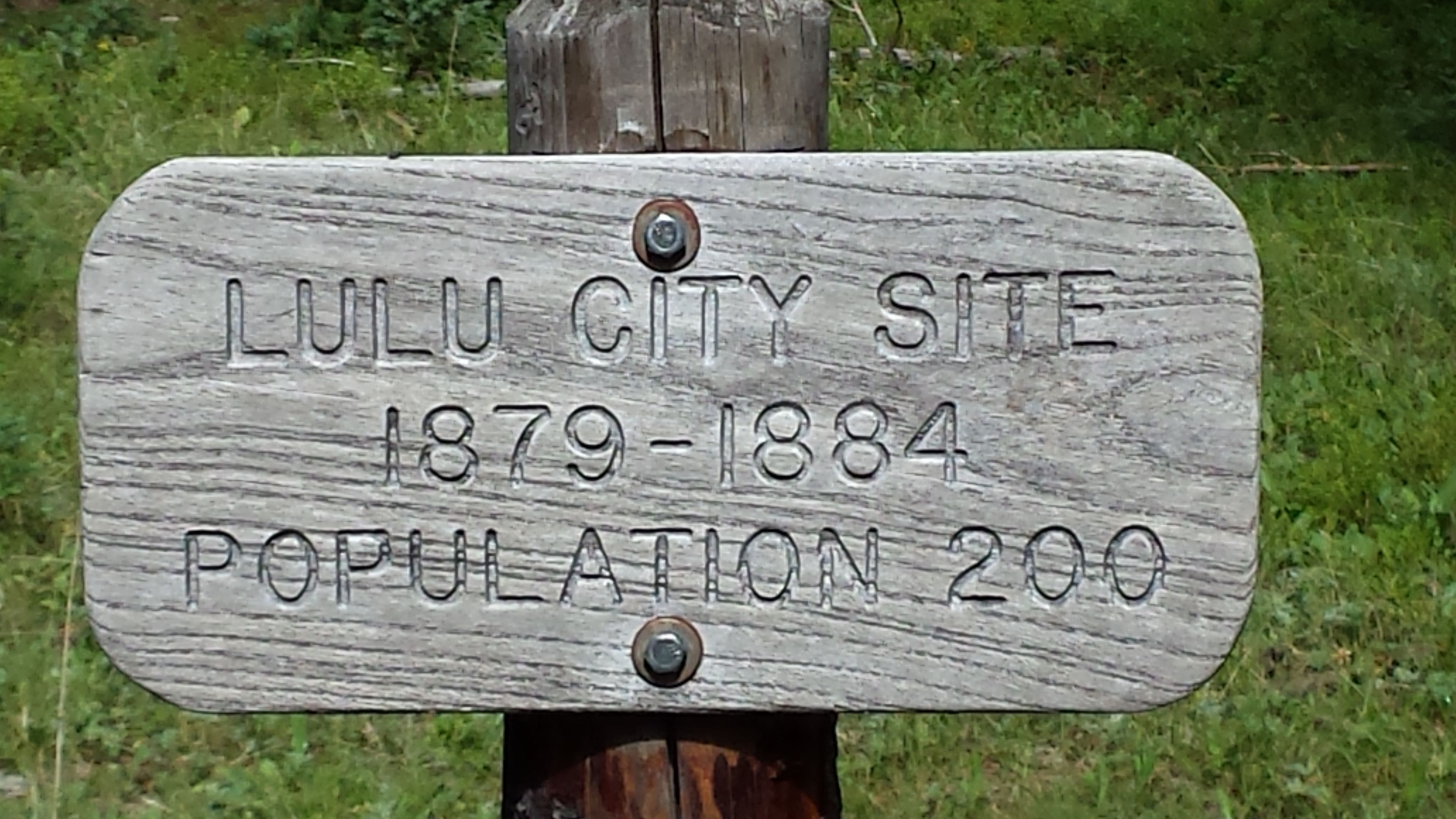 A wooden sign with the text "Lulu City Site 1879-1884 Population 200".