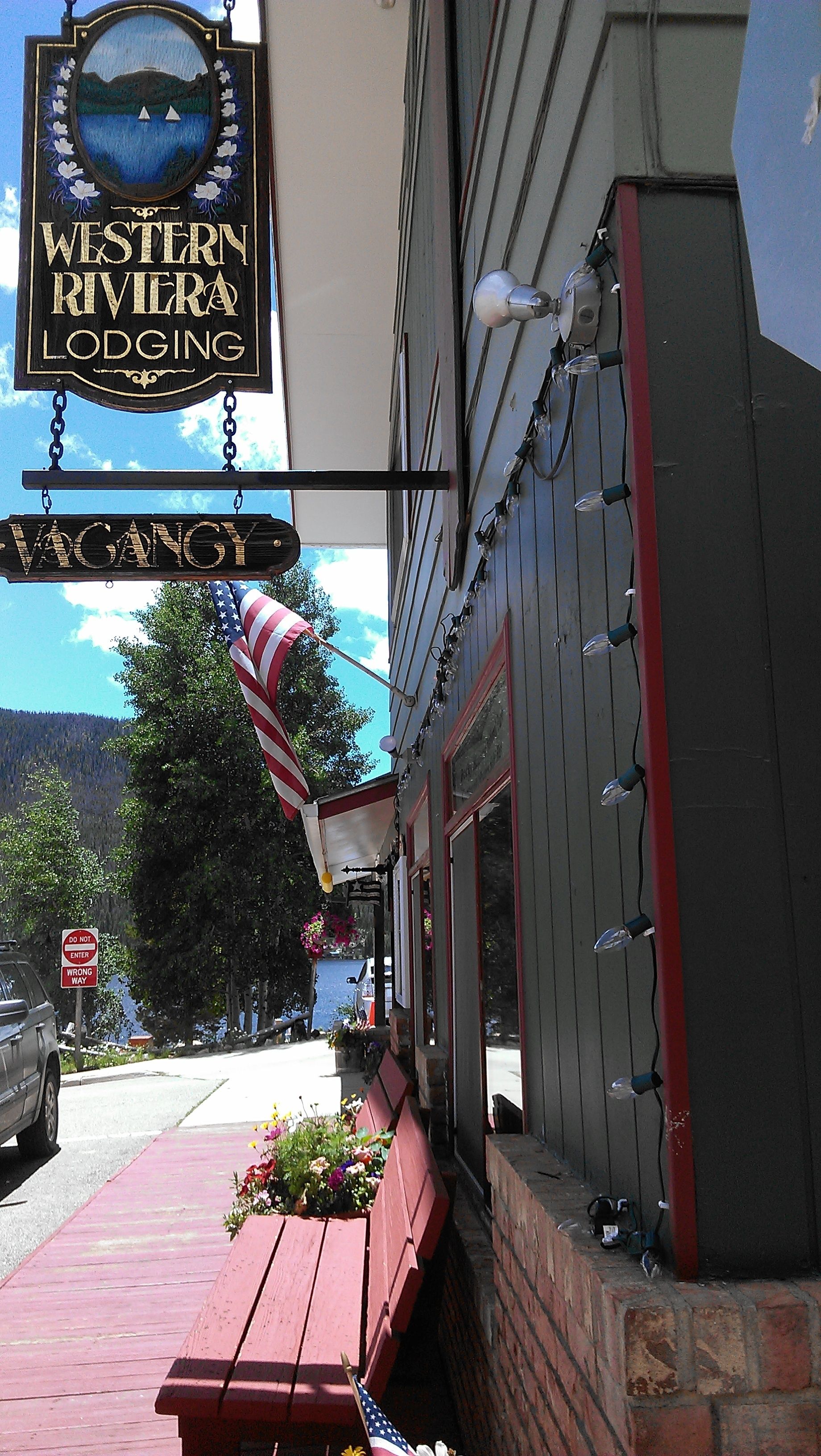 A Western Riviera Lodging sign, a vacant sign, and an American flag.