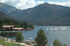 A lakeside hotel with a dock, sailboats, and mountains in the background.