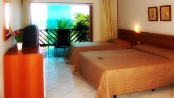 Quarto de hotel com duas camas, uma escrivaninha e varanda com vista para o oceano.