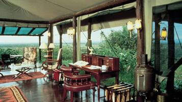 Una habitación con una mesa de madera, sillas, un escritorio y un ventanal con vistas al paisaje.