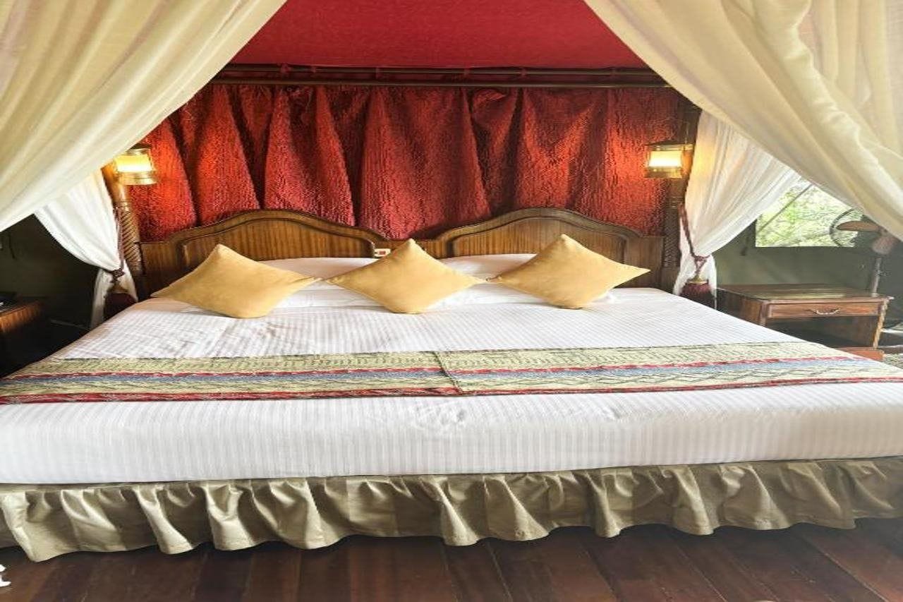 A bed with a canopy, a headboard, and two bedside lamps.