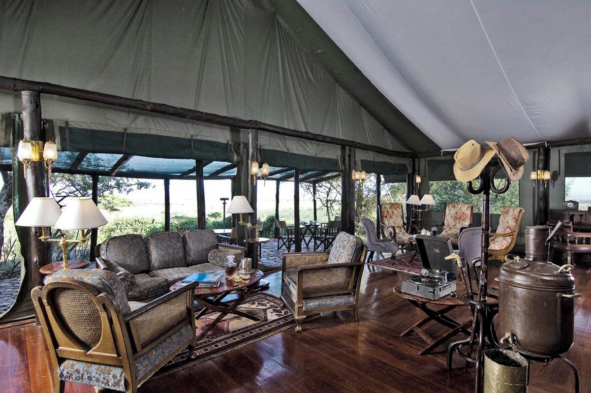 A tented outdoor lounge area with seating, tables, and a vintage radio.