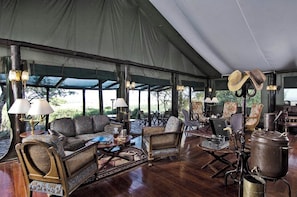 A tented outdoor lounge area with seating, tables, and a vintage radio.