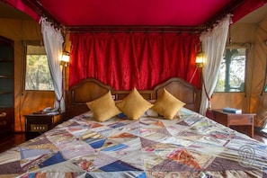 A bed with a quilt, a wooden headboard, and red curtains.