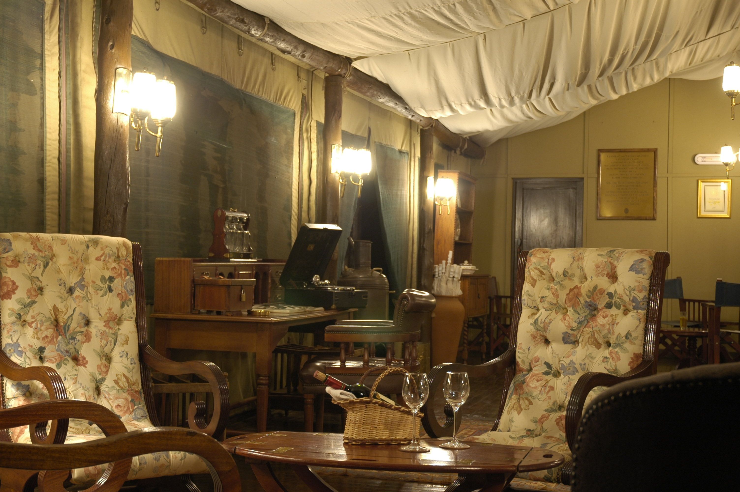A room with wooden furniture, a table with wine glasses, and a piano.
