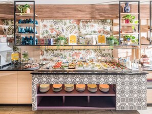 Un'area buffet con diverse opzioni gastronomiche, un angolo caffè e scaffali con stoviglie e oggetti decorativi.