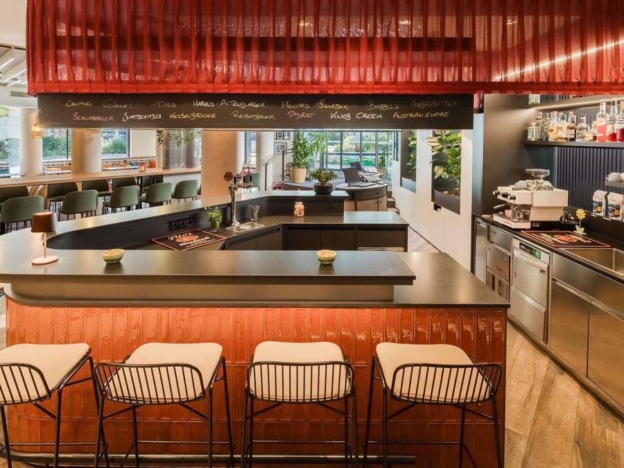A modern bar area with a central island, bar stools, and a variety of bottles on the shelves.