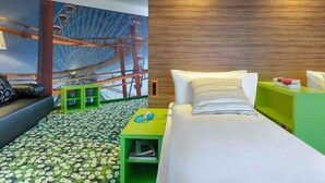 A hotel room with a bed, a green side table, a green nightstand, a wall mural of a Ferris wheel, and a patterned carpet. - Ibis Styles Wien City (Vienna)