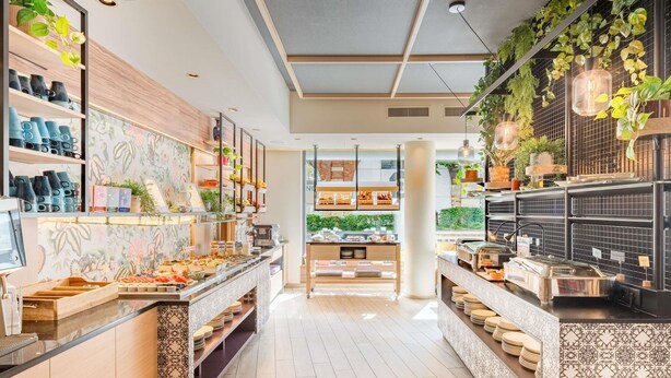 A modern buffet area with a variety of food options, wooden shelves, and decorative plants. - Ibis Styles Wien City (Vienna)