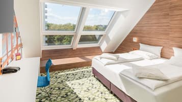 Ein modernes Schlafzimmer mit schrägen Wänden, einem großen Dachfenster, einem Bett mit weißen Bettwäsche und einem Teppich mit Blumenmuster.