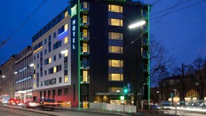 A hotel with a modern design, featuring a prominent 'ibis Styles' sign, multiple balconies, and a well-lit facade. - Ibis Styles Wien City (Vienna)