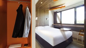 Een moderne hotelkamer met een bed, een bureau en een stoel.