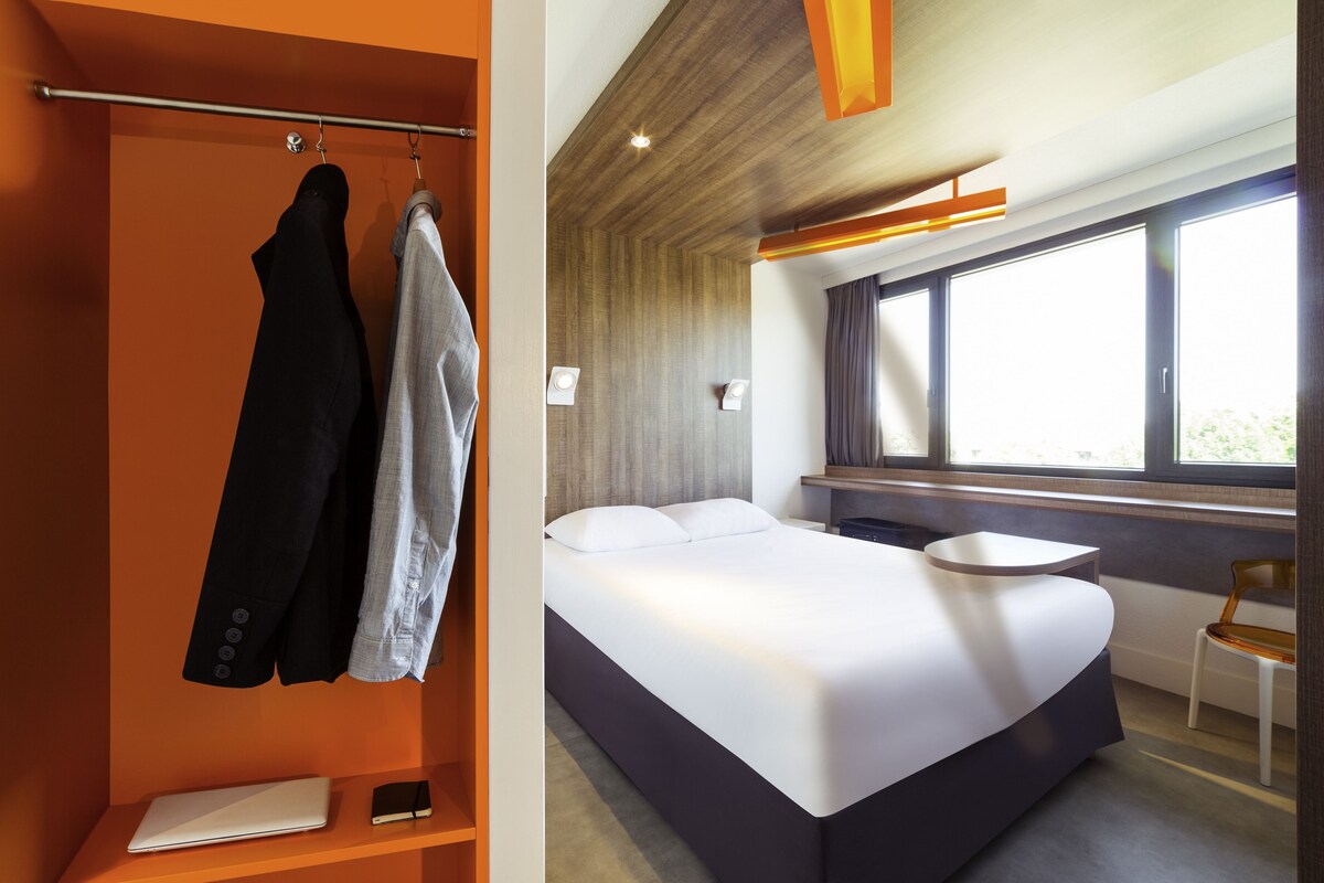 Une chambre d’hôtel moderne, équipée d’un lit, d’un bureau et d’une chaise.