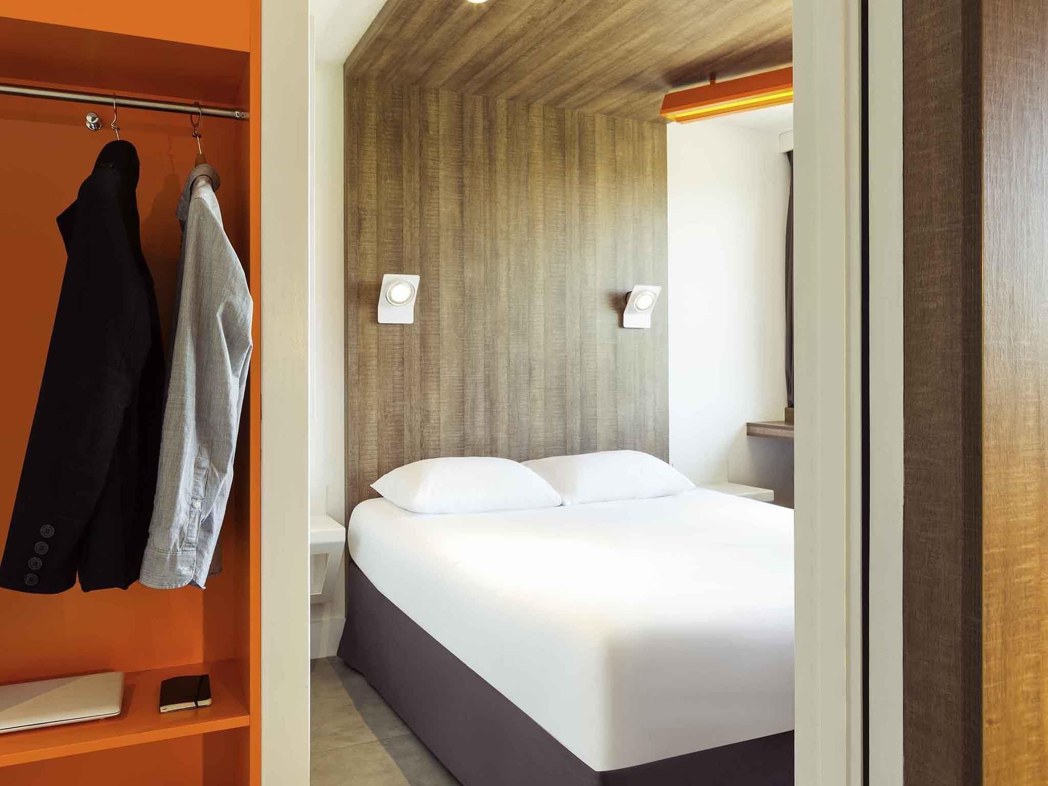 Una habitación de hotel con una cama, un armario y un espejo.