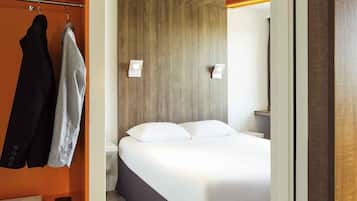 Una habitación de hotel con una cama, un armario y un espejo.