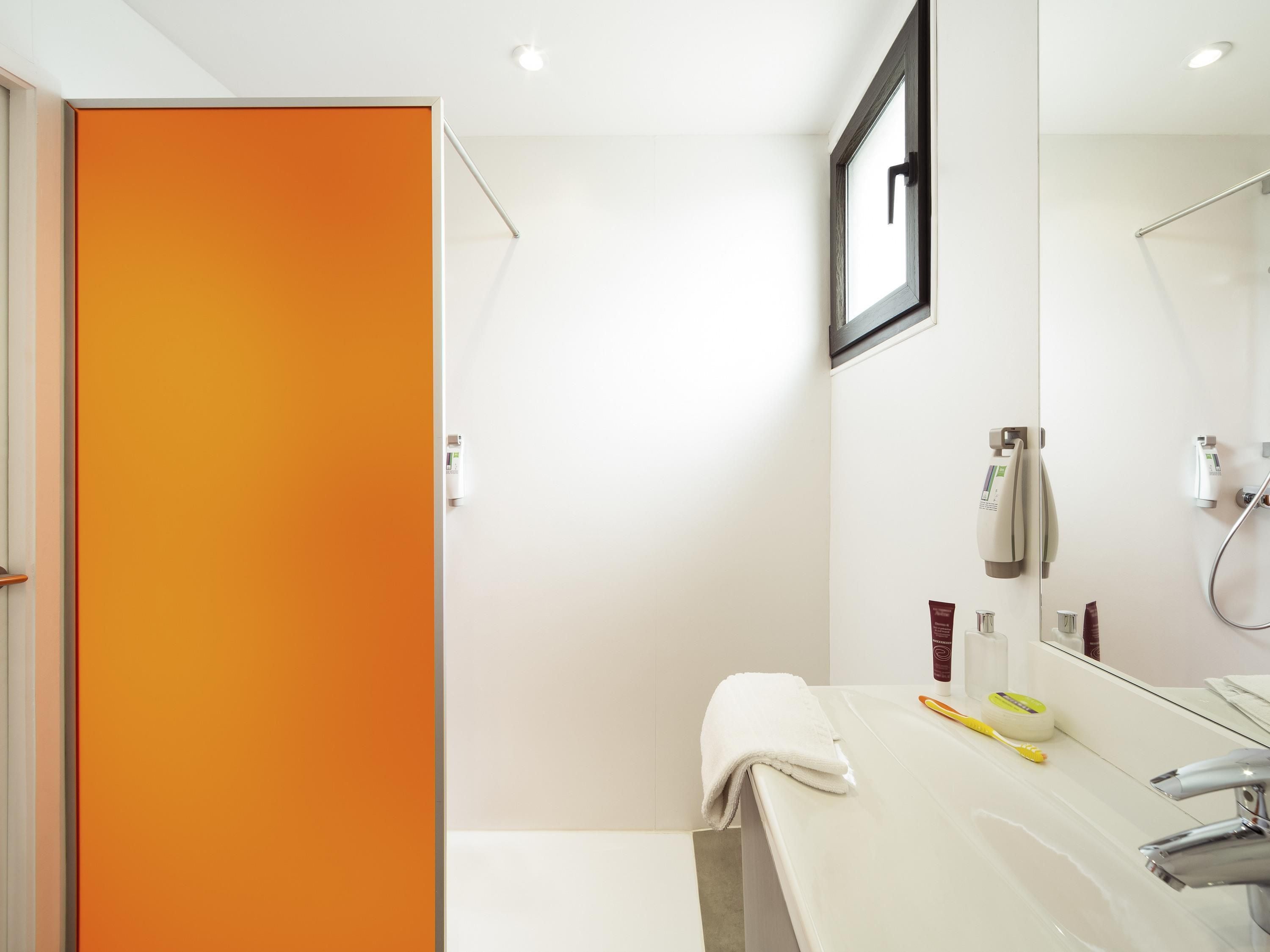 A modern bathroom with a white sink, a mirror, and a shower.