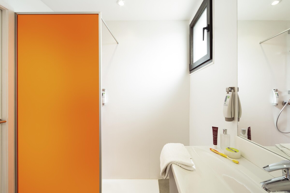 Une salle de bain moderne avec un lavabo blanc, un miroir et une douche.