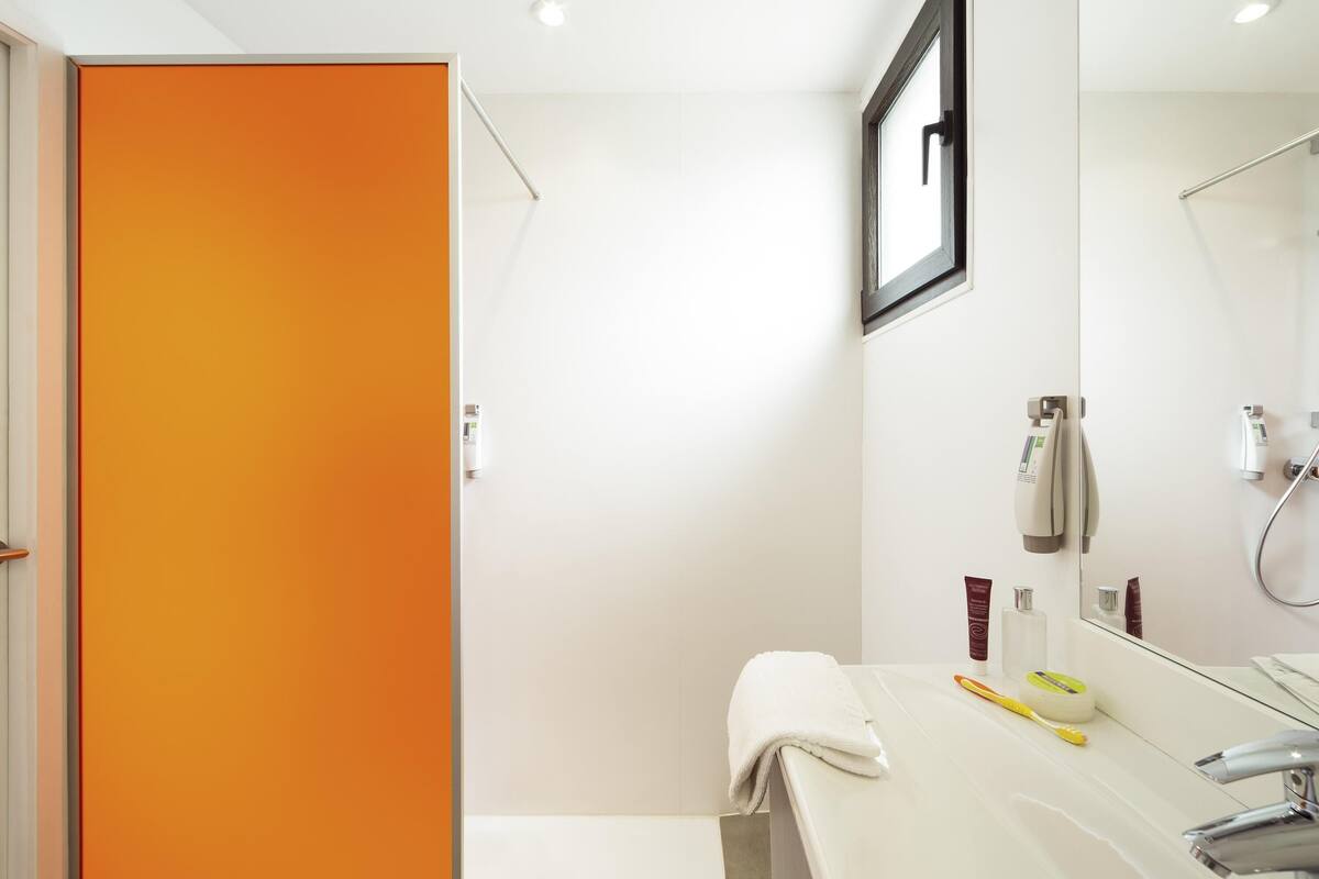 Een moderne badkamer met een witte wastafel, een spiegel en een douche.