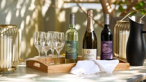 A table with wine bottles, glasses, and a candle holder. - Airport Apartments by Vetroblu (Redcliffe)