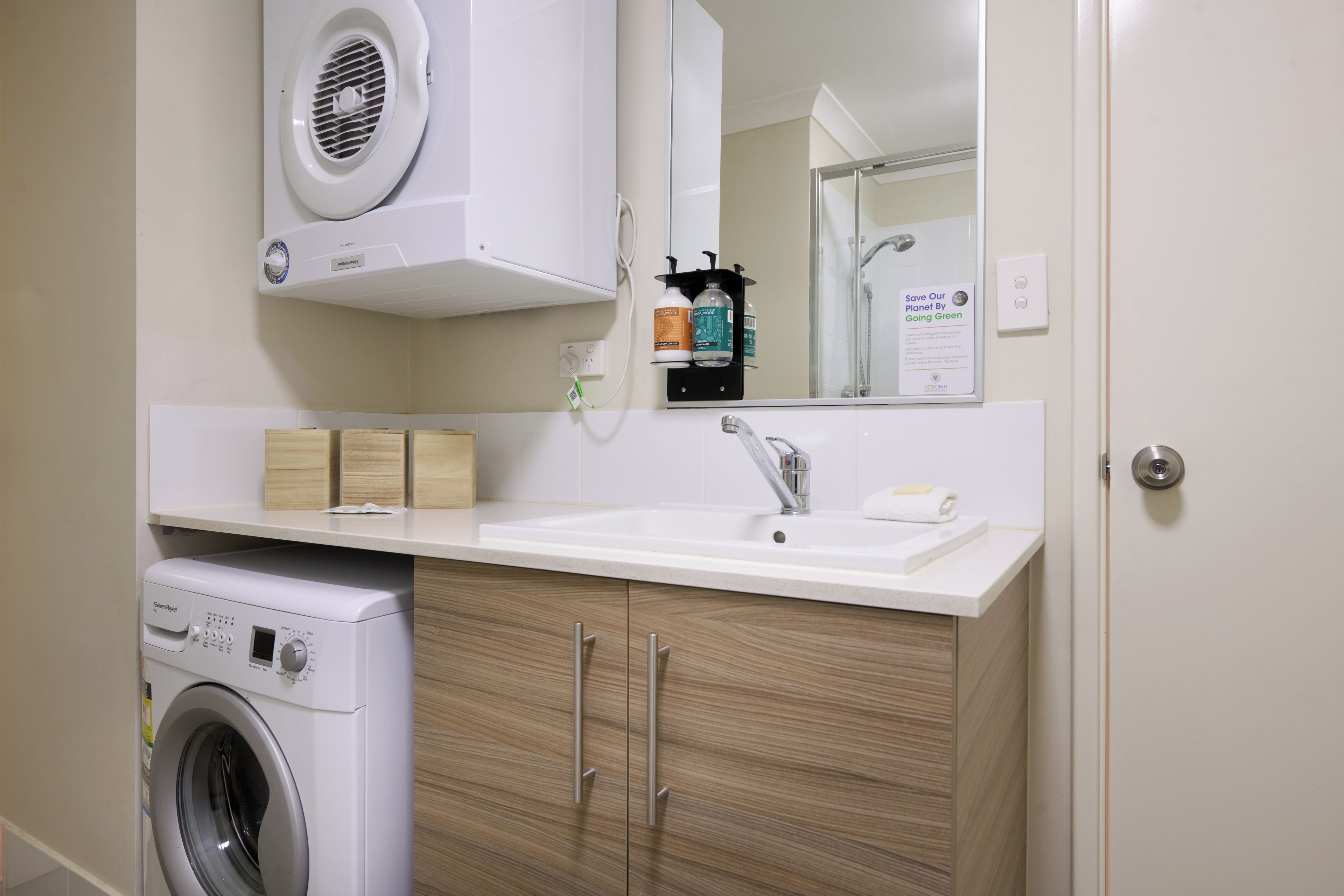 Un baño moderno con lavadora integrada, un lavabo y un espejo sobre el mostrador.