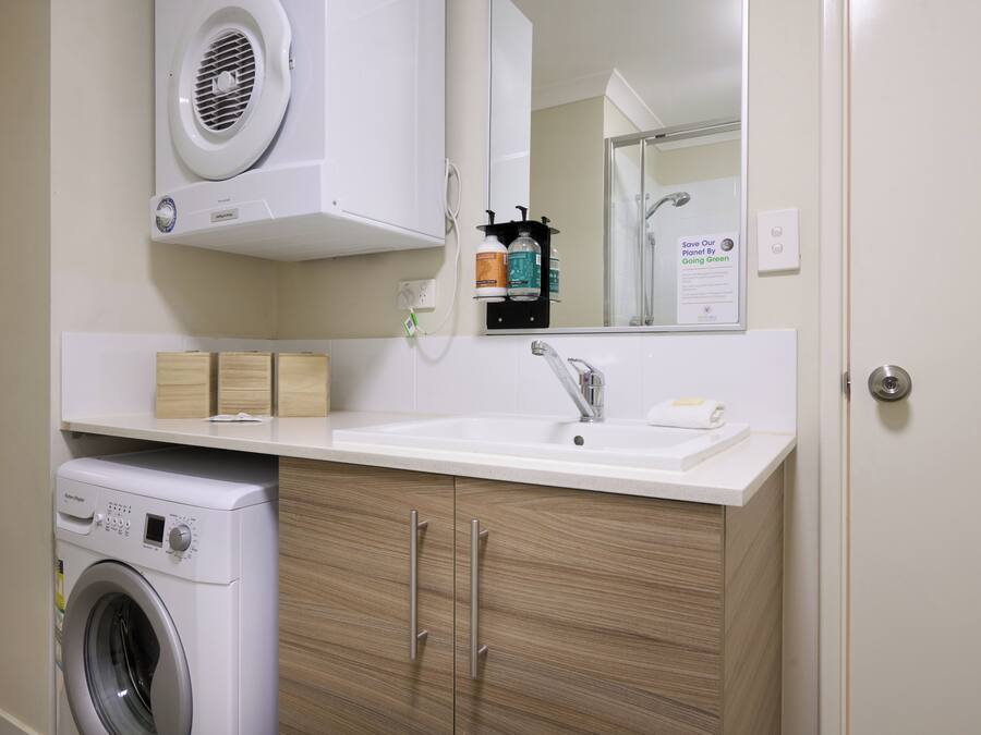 Een moderne badkamer met een ingebouwde wasmachine, een wastafel en een spiegel boven het aanrecht.