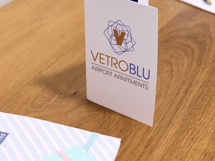 Tarjeta de presentación de Vetroblu Airport Apartments sobre una mesa de madera.