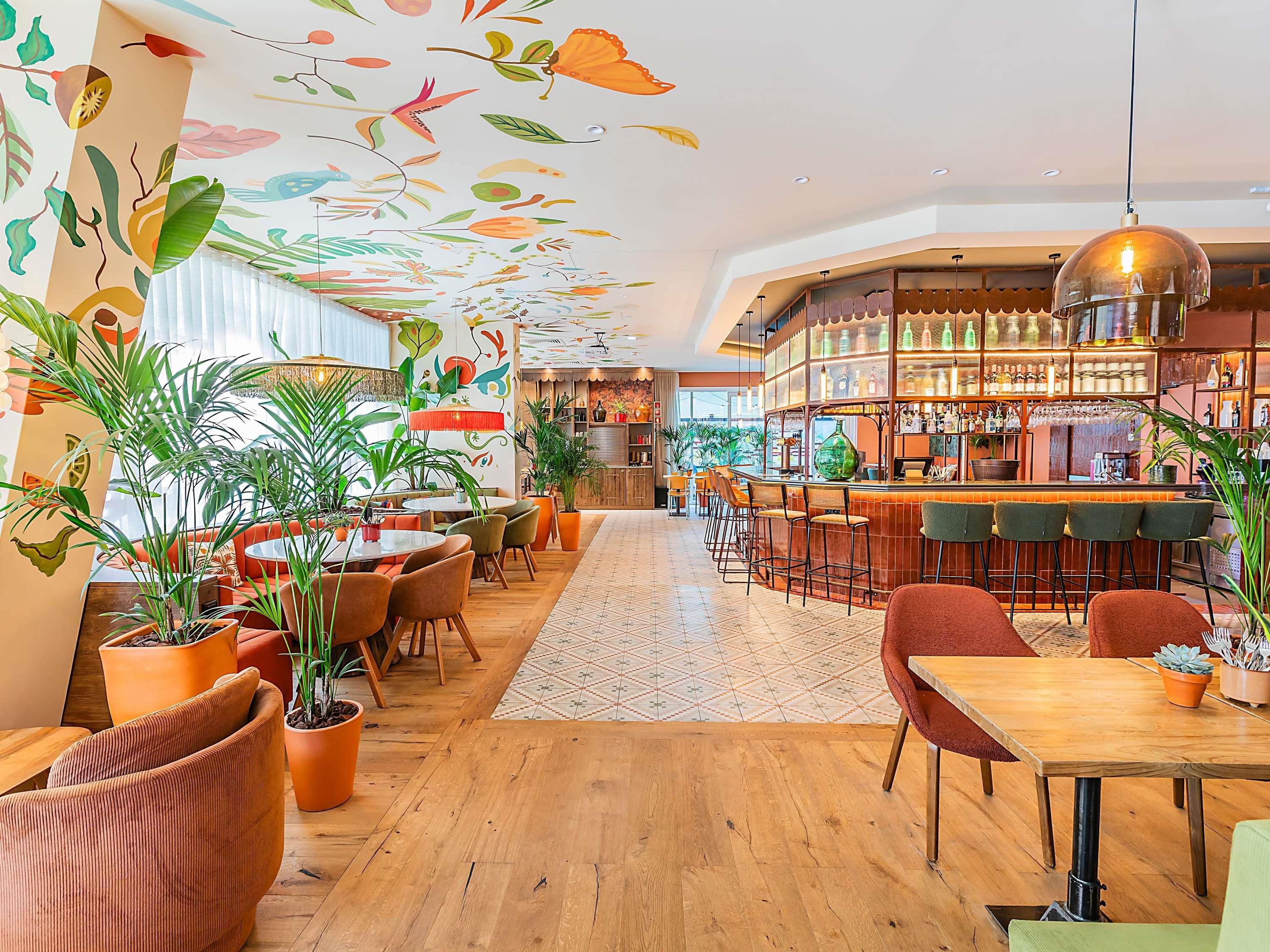 Un espace bar doté d’un plancher en bois, d’un comptoir et de plusieurs tabourets.