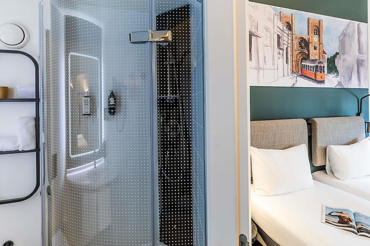 Een moderne badkamer met een douchecabine van glas, een handdoekrek en een zeepdispenser op de muur.