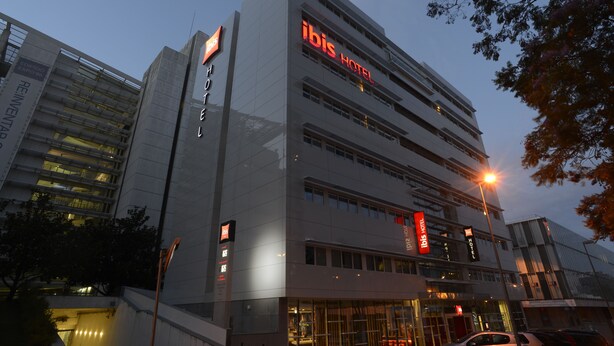 Een modern hotelgebouw met meerdere verdiepingen, opvallende borden en een goed verlichte ingang.