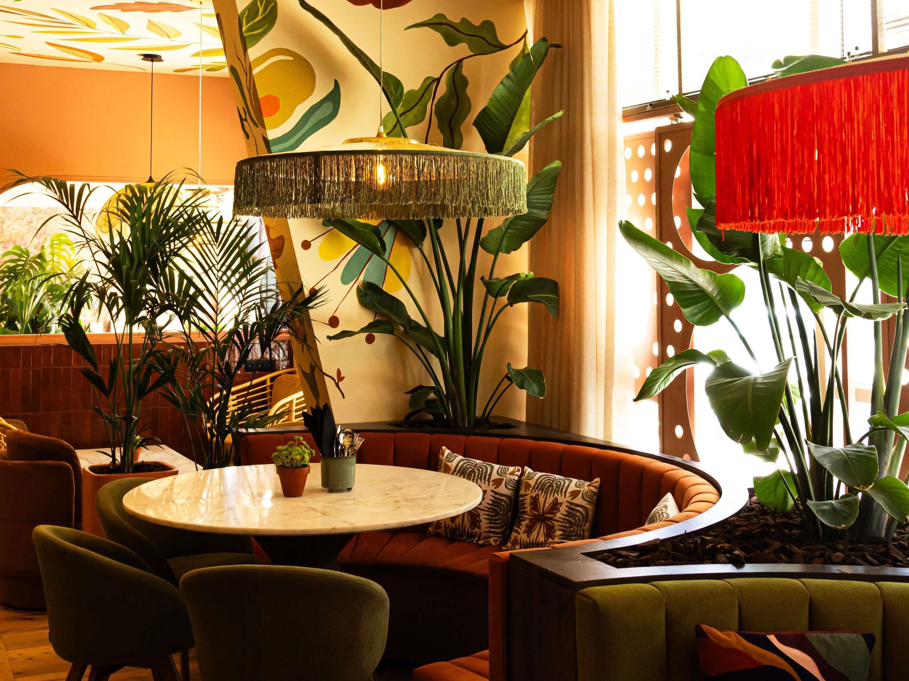 A modern interior with a round table, seating area, and potted plants.
