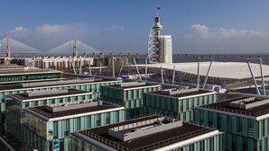 Een modern complex van gebouwen met meerdere hoge torens en een grote brug op de achtergrond.