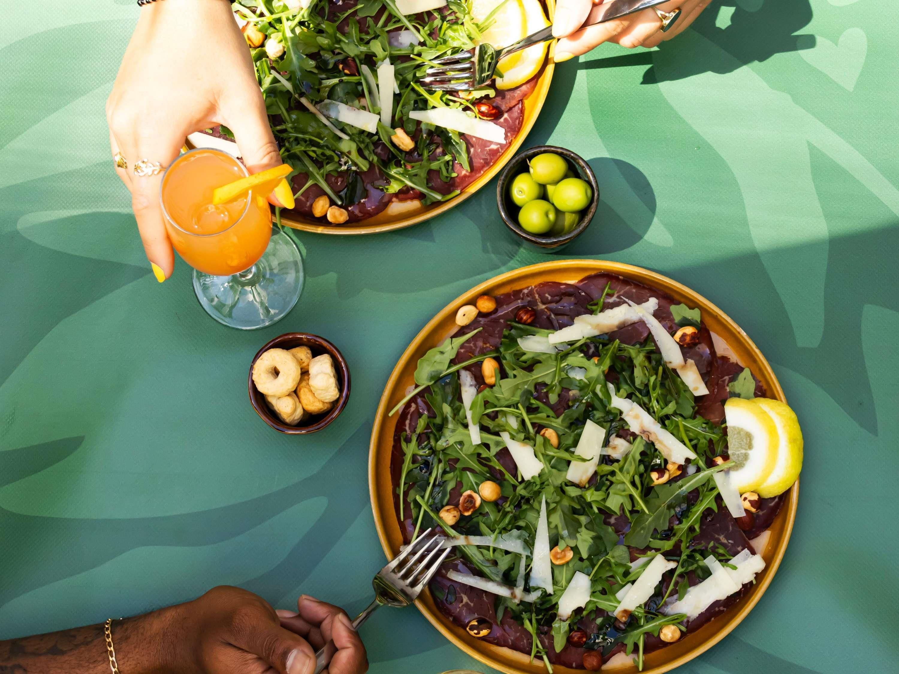 A table with two plates of food, a glass of orange juice, and a bowl of nuts.