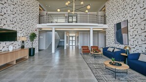 A spacious living area with a high ceiling, modern decor, and a view to a balcony.