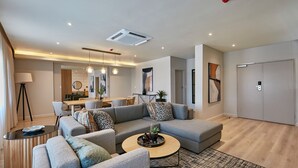 A modern living room with a sectional sofa, a round coffee table, and a dining area in the background.