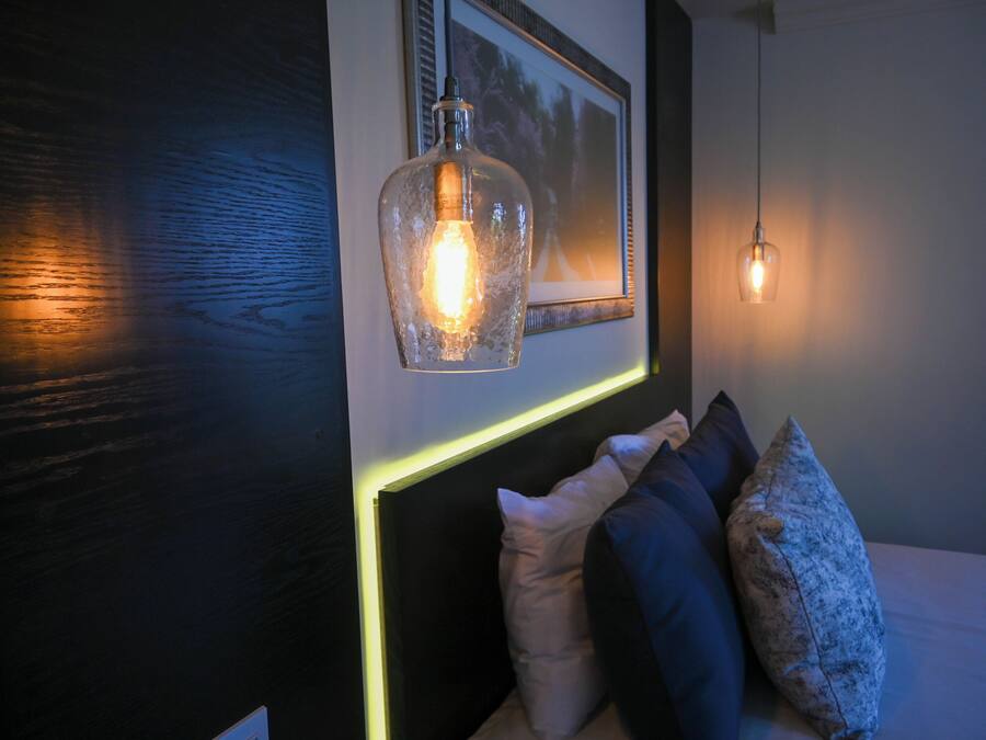 A bedroom with a bed, pillows, a framed picture, and two pendant lights.