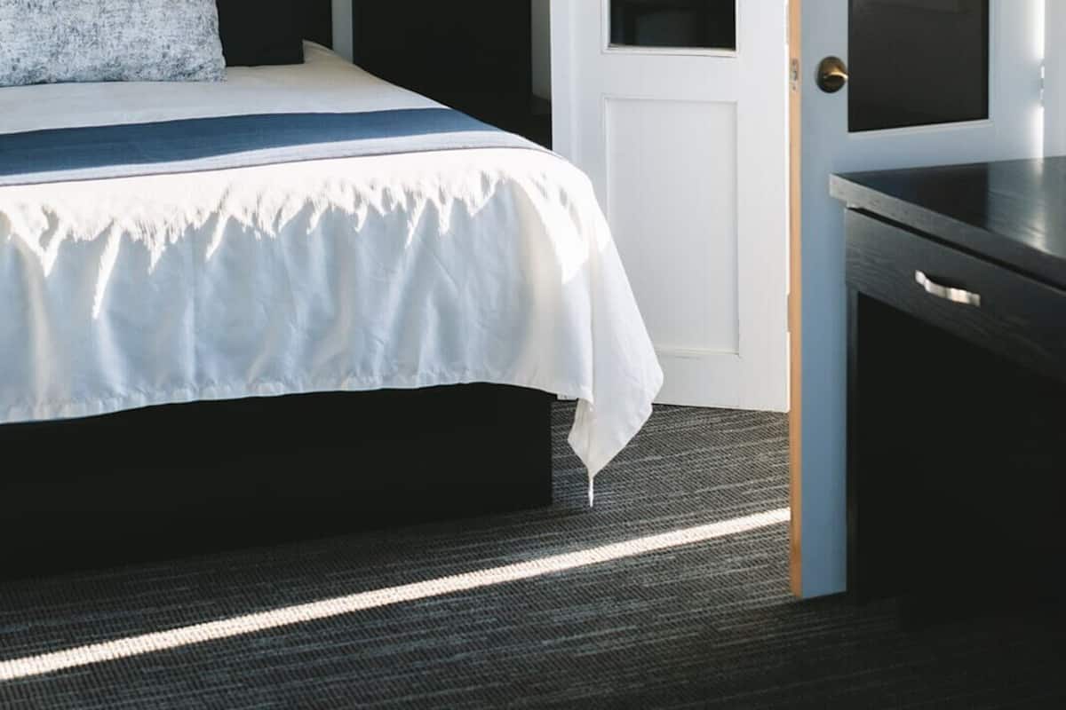 A bedroom with a bed, a hanging light, a door with a mirror, and a framed picture on the wall.