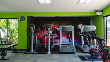 A gym with cardio machines, a bench, and a wall clock.