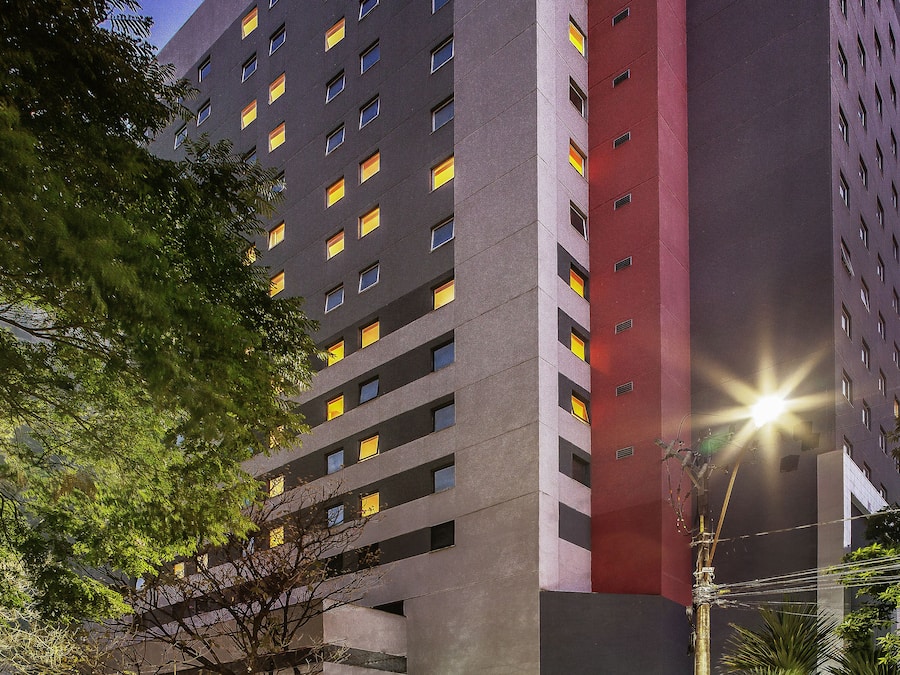 Um hotel de vários andares com fachada moderna, várias janelas e entrada visível com sinalização.