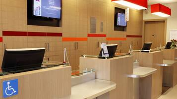 A hotel reception area with multiple counters, a television screen, and a wheelchair accessibility sign.