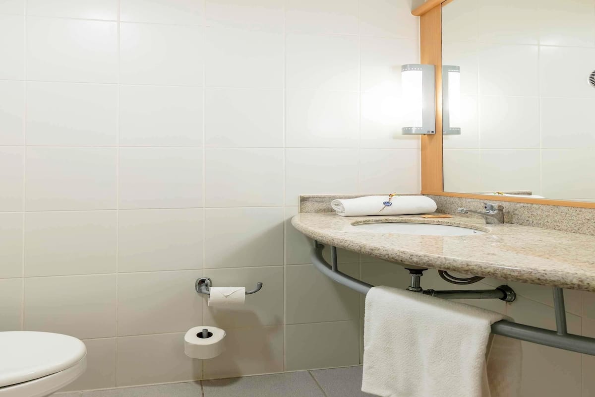A bathroom with a toilet, a sink with a towel, and a mirror.