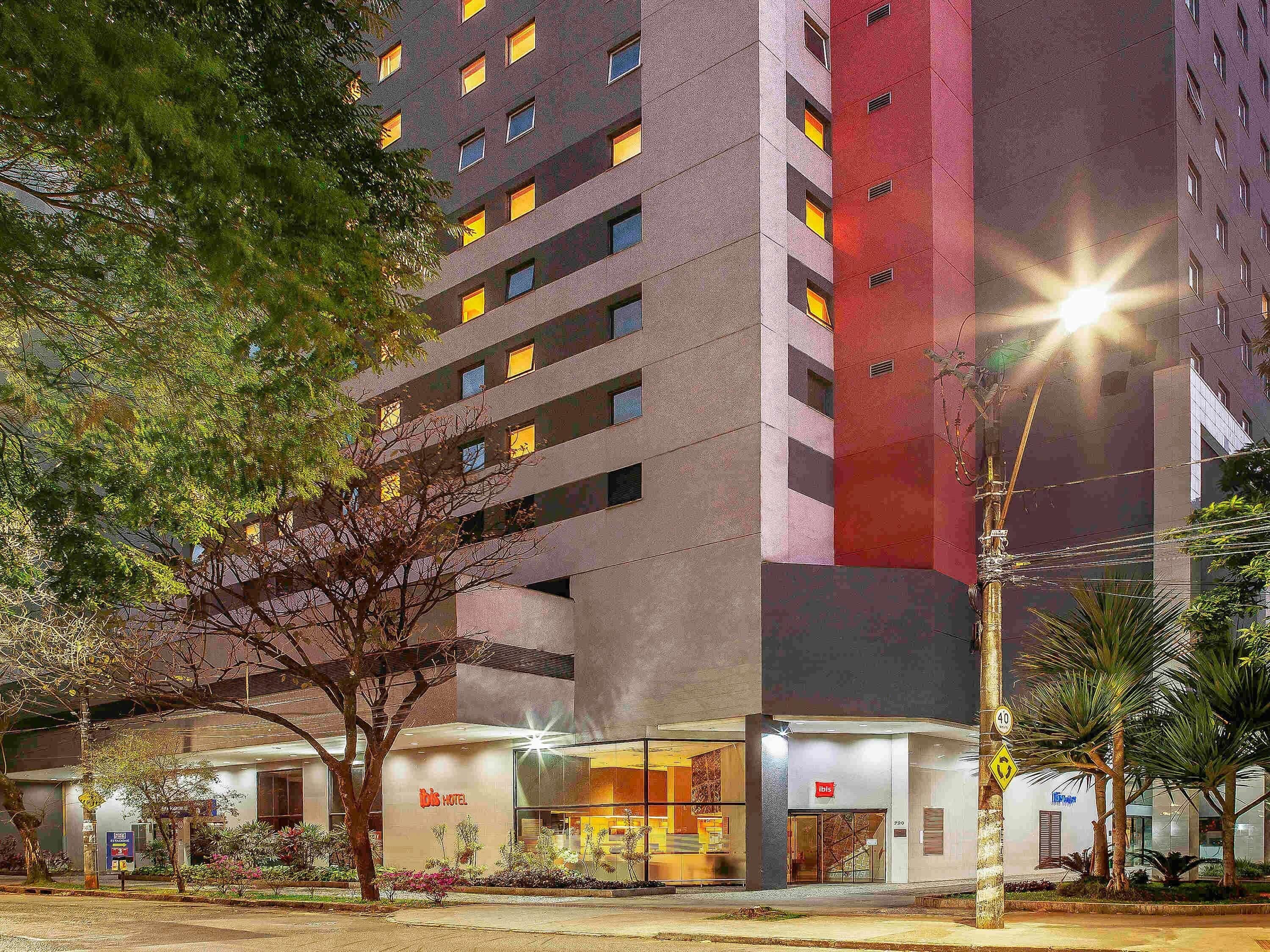 A hotel with multiple floors, a glass facade, and a well-lit entrance.