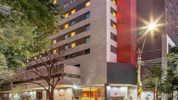 A hotel with multiple floors, a glass facade, and a well-lit entrance.