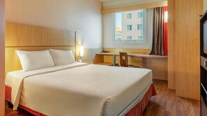 A hotel room with a bed, a desk, a chair, a TV, and a window with curtains. - ibis BH Afonso Pena Savassi (Belo Horizonte)