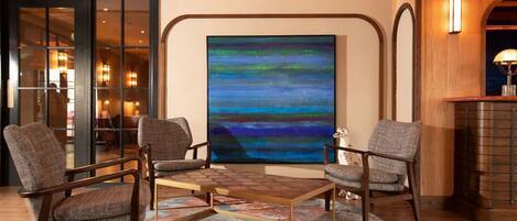 A modern living room with a large abstract painting, wooden furniture, and a fireplace.