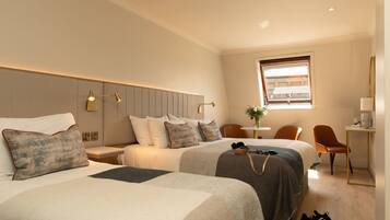 A hotel room with two beds, a desk, a chair, and a window.