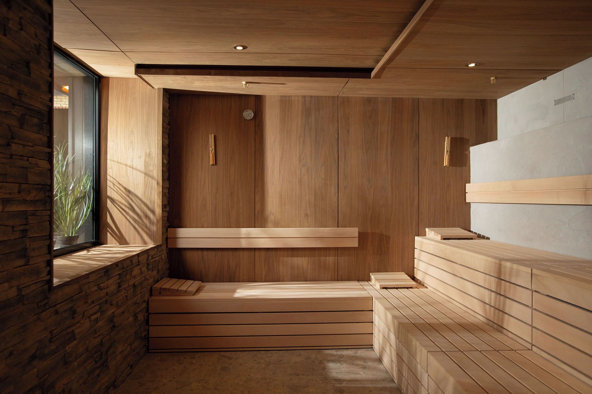 Un spa moderno con paredes de madera, una pared de acento de piedra y un ventanal.